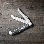 Case Pocket Worn Crandall Jig Gray Bone Mini Trapper pocket knife with Clip and Spey blades open, on a rustic wood surface