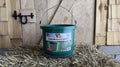  Green heated bucket with metal handle on hay
