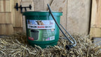 Green heated bucket with electric cord on hay
