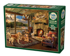 Lakeside Cabin 1000-piece puzzle box featuring dogs by a stone fireplace overlooking a lake
