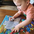 Child placing a piece in the Undersea Turtle tray puzzle showing sea creatures and an underwater scene