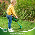 Child using a green Scotts toy weed trimmer outdoors