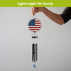 Person holding the American flag wind chime by its hanging hook, showing the full panel, black tubes, and blue wind catcher.