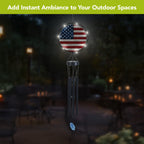 American flag wind chime hanging outdoors at night with LED lights illuminating the round flag panel.
