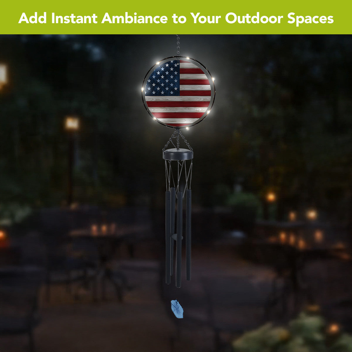 American flag wind chime hanging outdoors at night with LED lights illuminating the round flag panel.