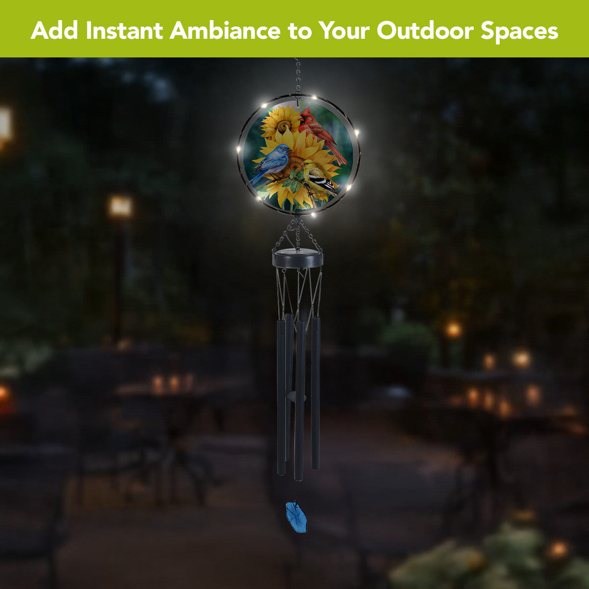 Birds in the Garden solar wind chime glowing outdoors at night, with LED lights around the glass artwork.
