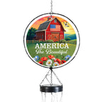 Red barn, American flag, and flowers on glass wind chime artwork reading “America the Beautiful.”