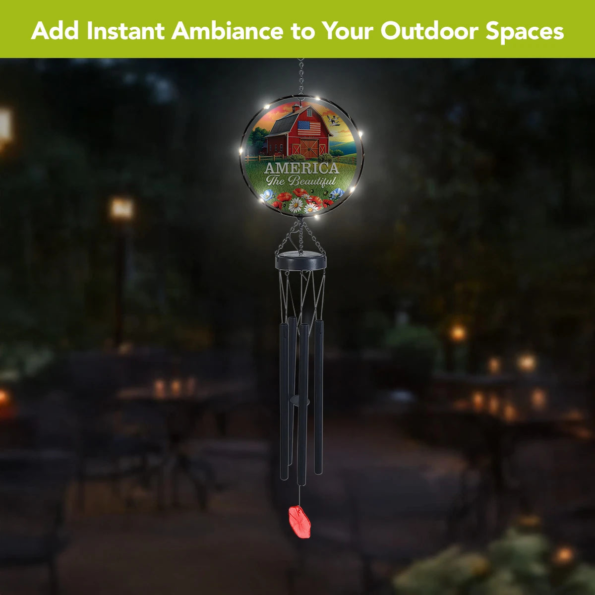 American Barn solar wind chime hanging outdoors at night with LED lights glowing around the glass artwork.