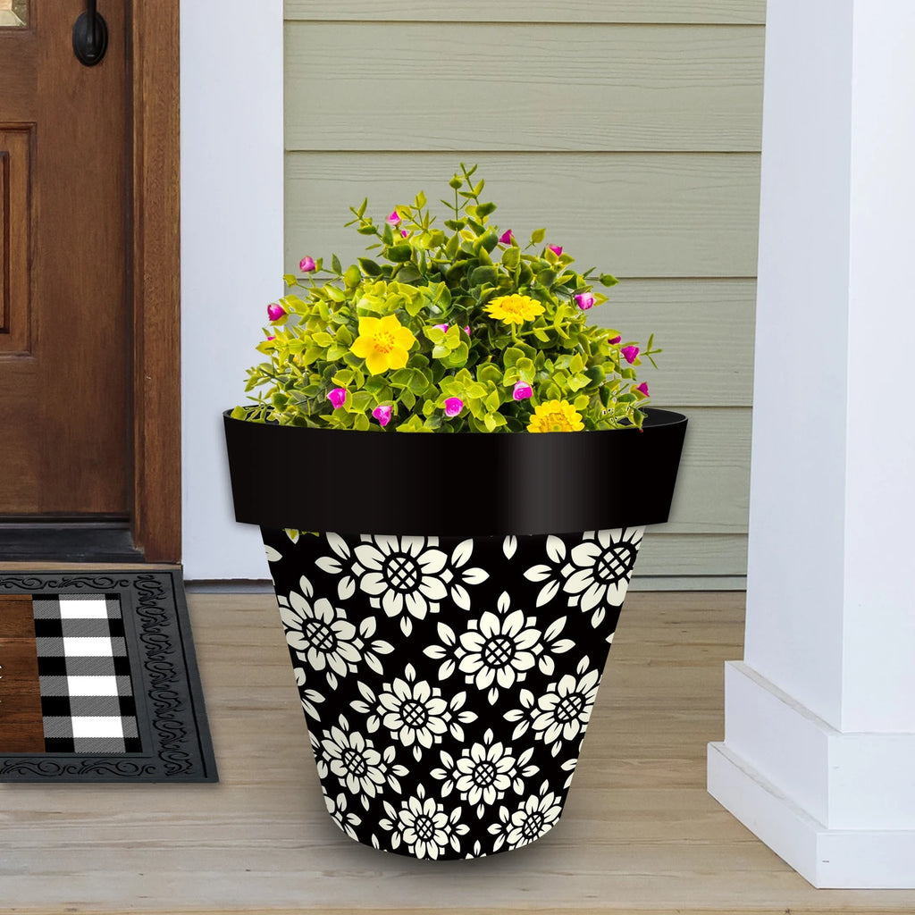 Black and cream Geometric Floral planter filled with yellow and pink flowers beside a front door.