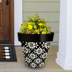 Black and cream Geometric Floral planter filled with yellow and pink flowers beside a front door.
