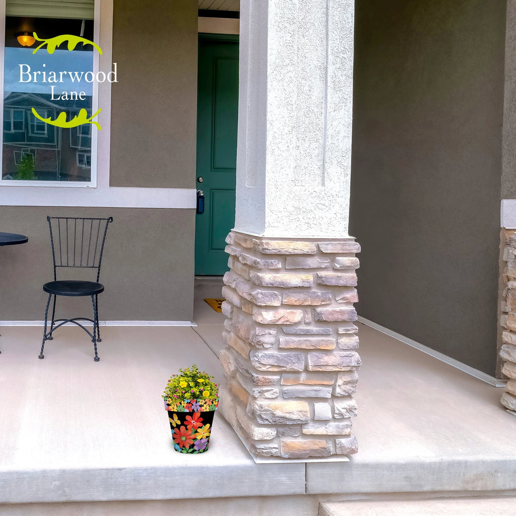 Colorful Whimsy Flowers planter filled with flowering plants beside a stone column on a front porch.