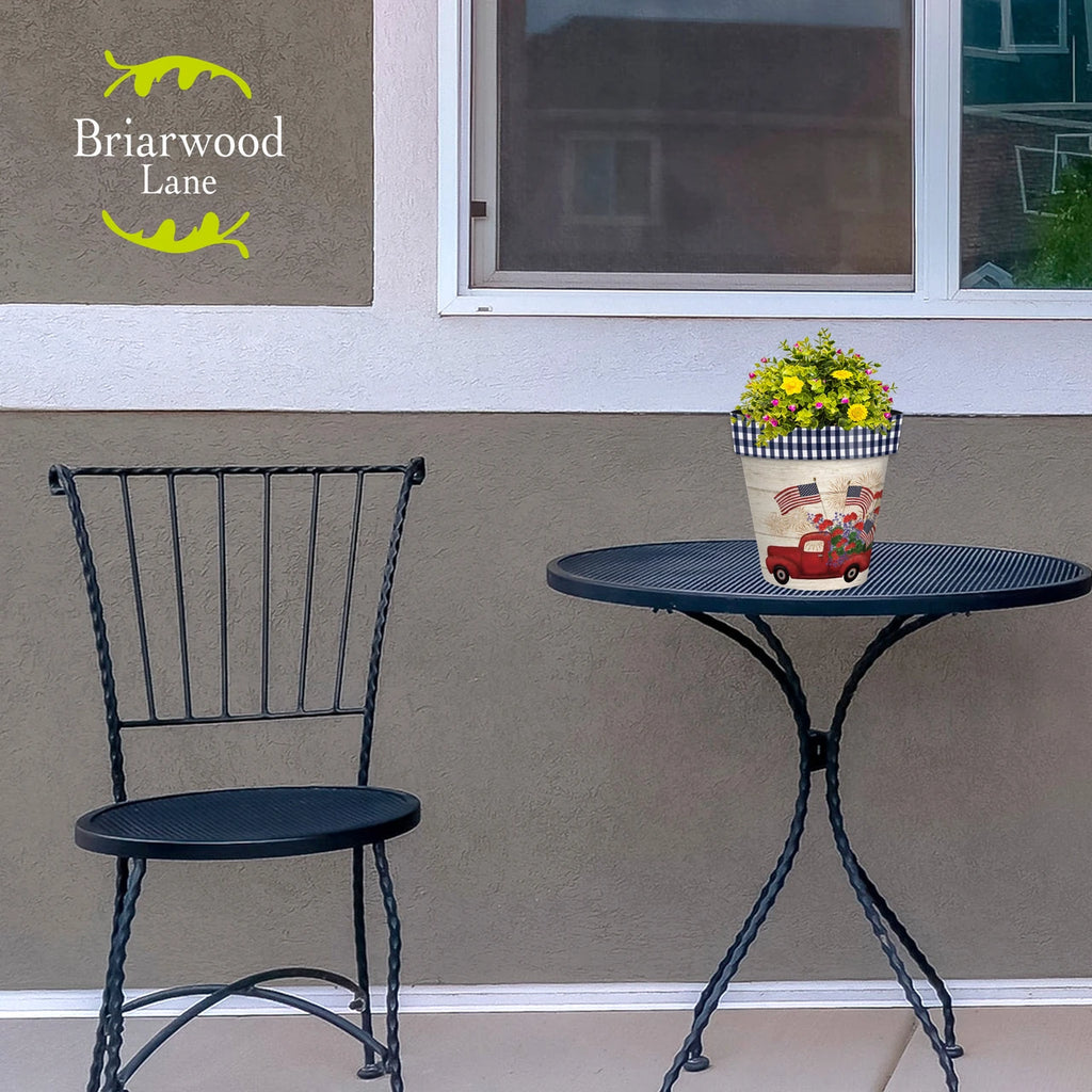 Stars and Stripes Truck planter filled with flowers on a black patio table beside a matching chair.