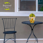 Sunflower Duo planter filled with yellow and pink flowers on a black metal patio table.