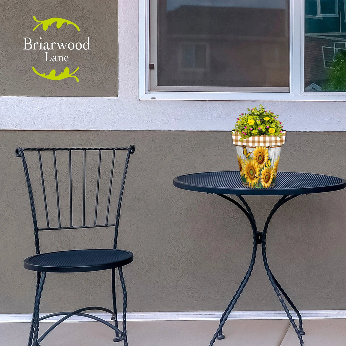 Sunflower Duo planter filled with yellow and pink flowers on a black metal patio table.