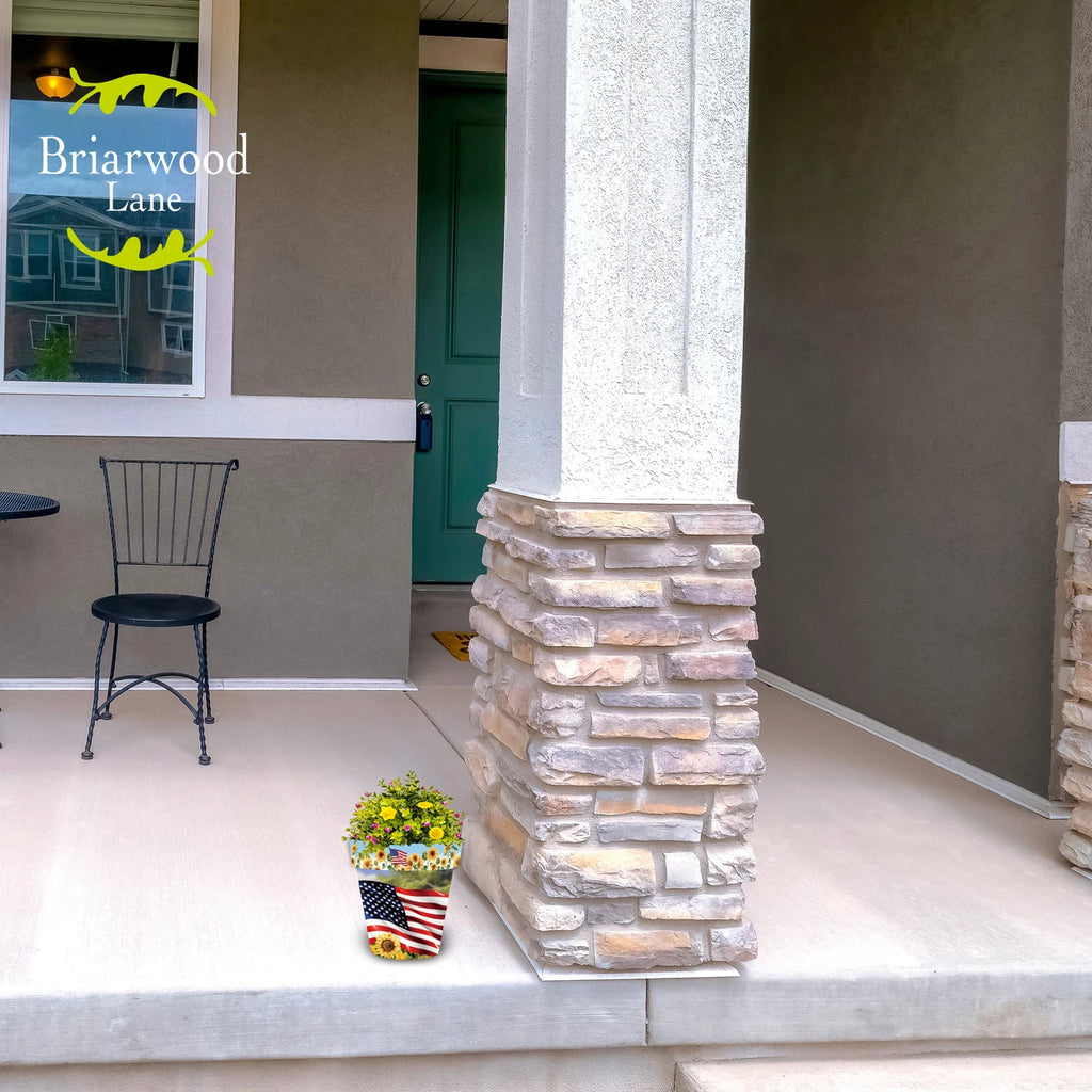 American Sunflowers planter filled with yellow and pink flowers beside a stone column on a front porch.