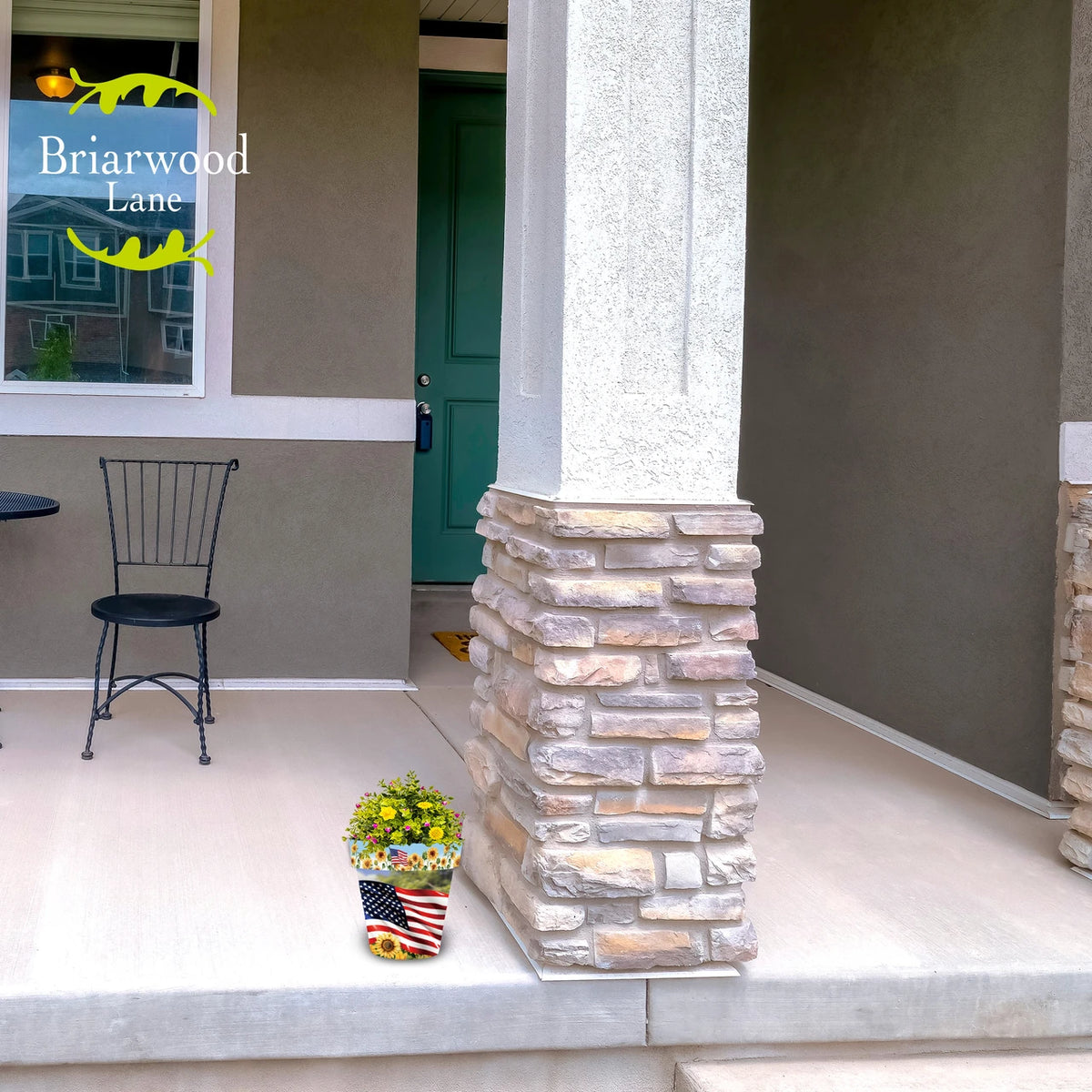 American Sunflowers planter filled with yellow and pink flowers beside a stone column on a front porch.