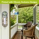 A hanging wall-mounted light fixture with a clear glass shade and a white metal frame, shown hanging on a wooden post in an outdoor patio setting with a green garden background.