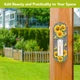 Checkered Sunflowers metal thermometer mounted on a wooden post beside a green lawn and garden.