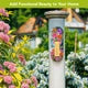Zinnias in Bloom metal thermometer mounted on a white garden post surrounded by flowers.