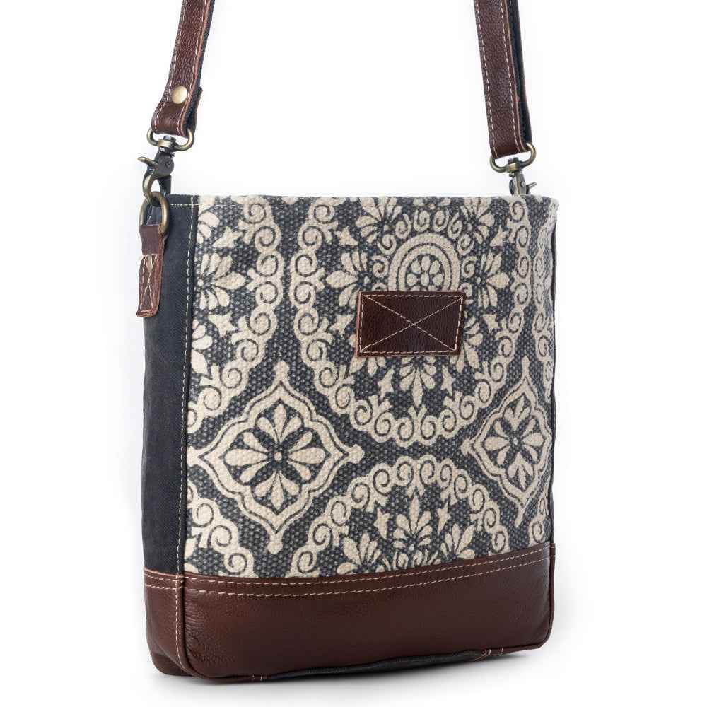 Angled view of Myra Freaky Leather Shoulder Bag with cream and dark floral rug pattern and brown leather trim