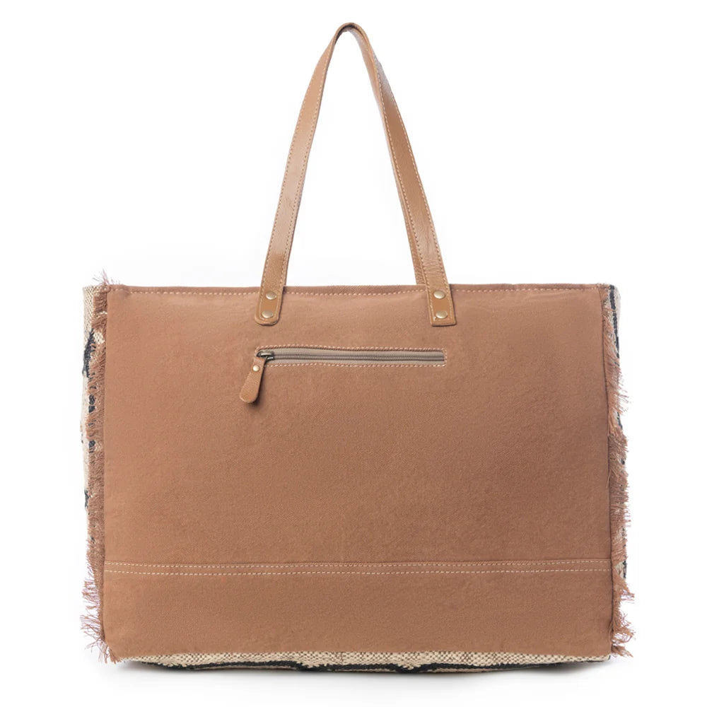 Back view of the Myra Kaliko Hill Canvas Weekender Bag with brown canvas, leather shoulder handles, and exterior zipper pocket.