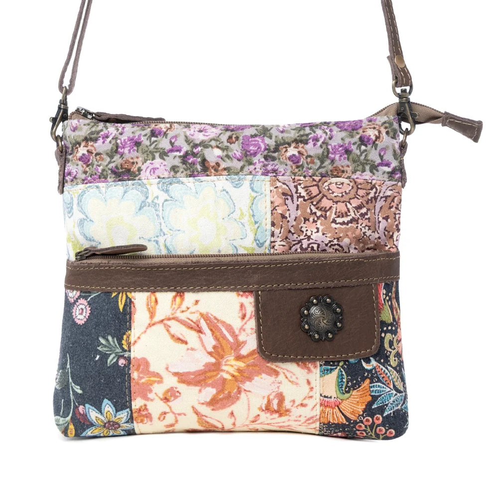 Front view of Myra La Fleur Patchwork Crossbody Bag with colorful floral canvas panels, brown leather accents and adjustable strap