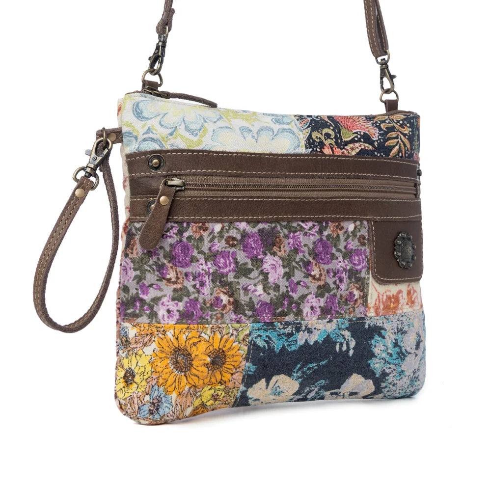 Angled view of Myra Le Piccolo Crossbody Bag with colorful floral canvas, genuine leather accents and wrist strap