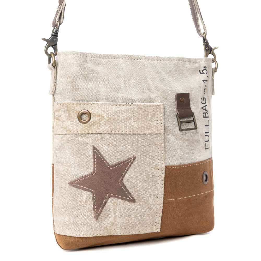 Angled view of Myra Leather Star Crossbody Bag with beige canvas, brown leather star detail and adjustable strap
