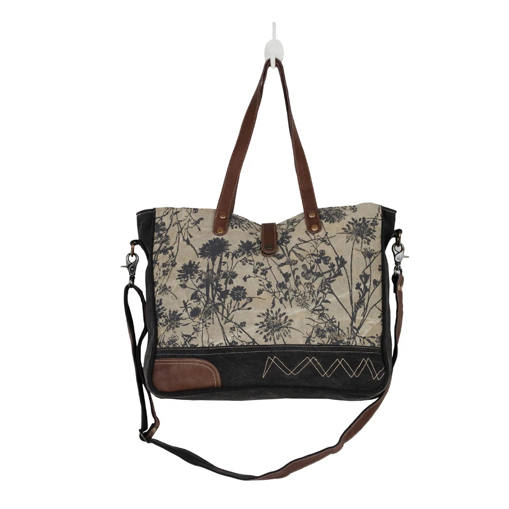 Front view of Myra Mystique canvas messenger bag with vintage floral print, leather handles and adjustable crossbody strap.