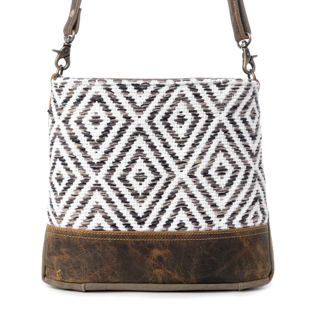 Front view of Myra Precision Crossbody Bag with black and white geometric rug design and brown genuine leather trim