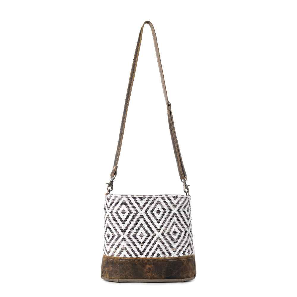 Full view of Myra Precision Crossbody Bag with black and white geometric rug design, genuine leather trim and adjustable shoulder strap