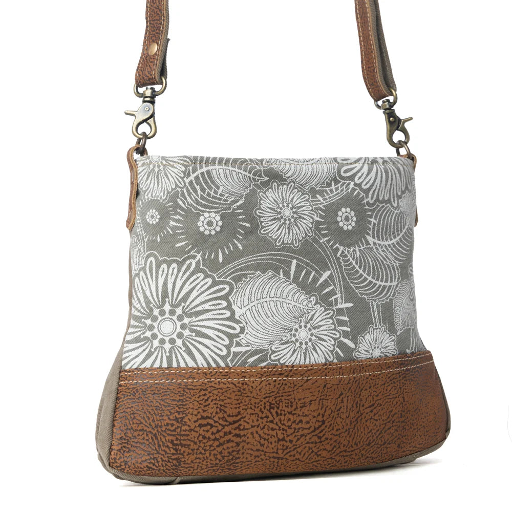 Angled view of Myra Saplings Shoulder Bag with white floral print canvas, brown leather accents and shoulder strap