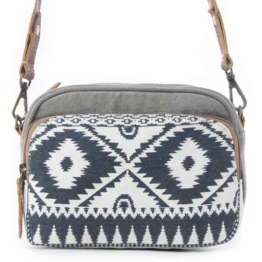 1. Front view of the Myra Temptation Tribal Crossbody Bag featuring a black and white geometric pattern, gray canvas, and leather strap.