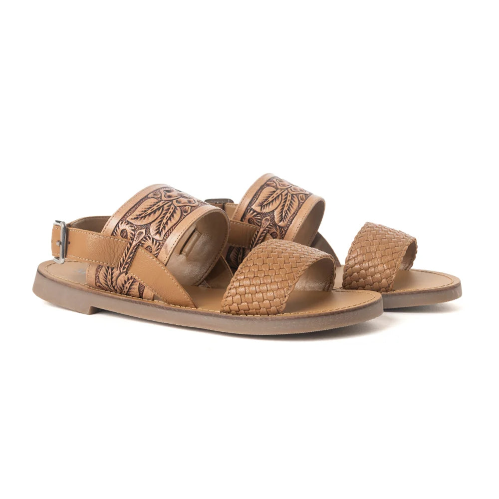 Angled view of Myra Pinehorn leather sandals showing floral tooling, textured toe straps, and buckle heel straps.