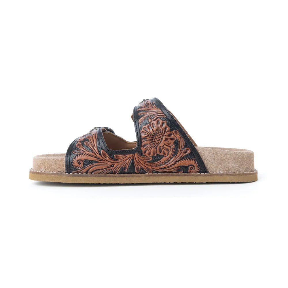 Side view of a Myra Canyon Ember sandal showing brown floral tooling on black leather and a low-profile sole.