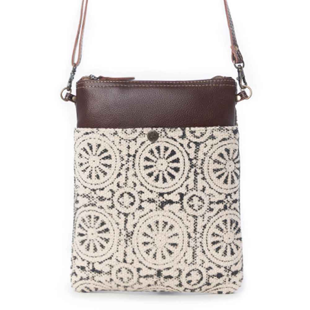 Myra Ruggy crossbody bag with a cream and dark gray geometric front panel, brown leather trim, and shoulder strap.