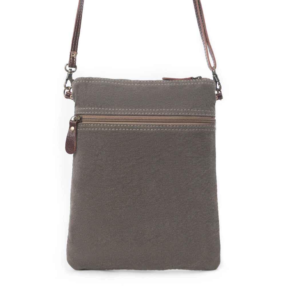 Back of Myra Ruggy crossbody bag showing gray canvas, a zippered pocket, and brown leather strap attachments