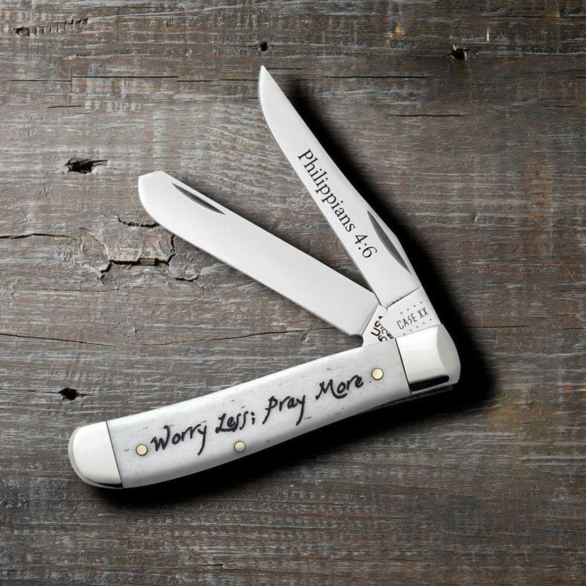 Case Worry Less, Pray More Smooth Natural Bone Mini Trapper pocket knife with both blades open on a rustic wood surface, Philippians 4:6 on the Clip blade