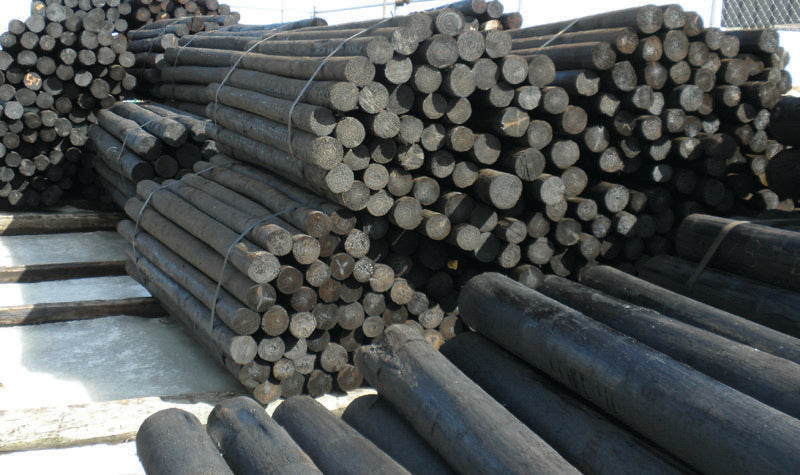Bundles of creosote-treated fence posts in a storage yard