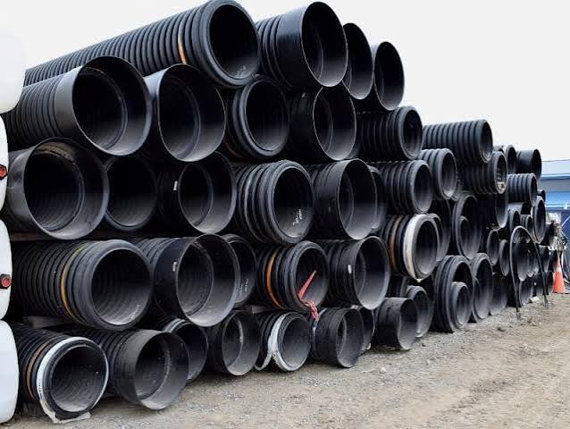 Stacks of black corrugated culvert pipes in assorted diameters