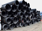 Stacks of black corrugated culvert pipes in assorted diameters